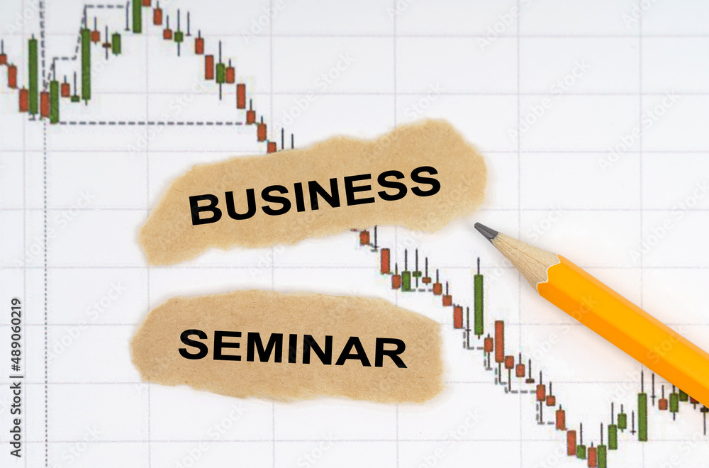 On the table with charts of quotes are a pencil and pieces of paper with the inscription - BUSINESS SEMINAR