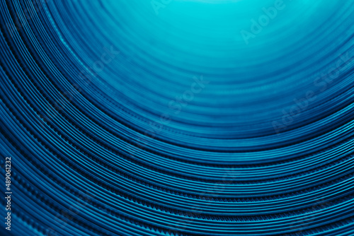Ridged texture. Blur glow background. Embossed steel gear wheels. Defocused neon blue color light reflection on dark curved corrugated abstract overlay.