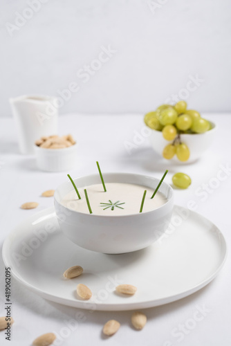 Crema de almendras, sopa fría española. Ajo blanco de Málaga con almendras y uvas en un recipiente blanco sobre una mesa blanca 