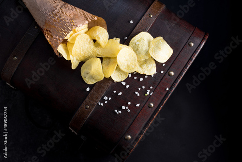 Patatas fritas saladas en un cono de papel. Aperitivo sobre fondo oscuro. Vista superior photo