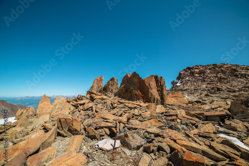 Scenic mountain landscape with old rocks and stones in sunlight. Awesome alpine scenery with stone outliers on high mountain under blue sky in sunny day. Sharp rocks in sunshine at very high altitude.