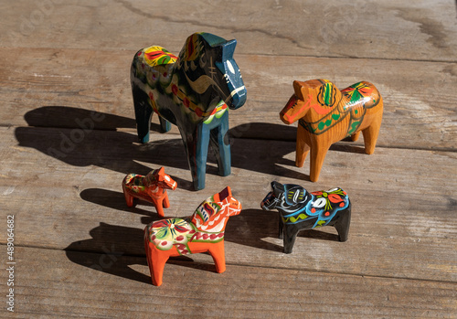 A group of Swedish wooden Dala horses in various colors on a rustic wooden tabletop photo