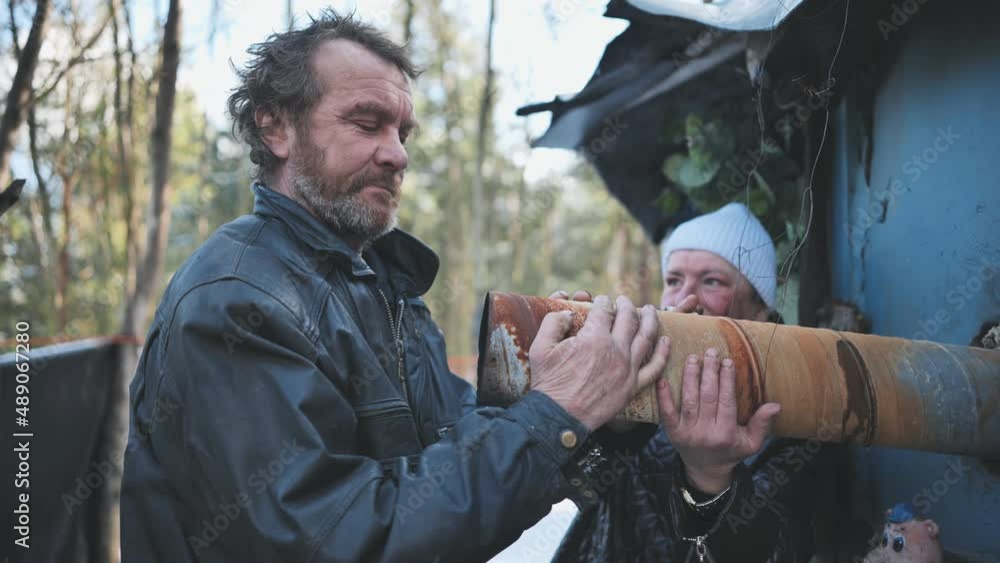 Homeless people warming their hands on the chimney of their hut in winter in the woods. Homeless people warming their hands on the chimney of their hut in winter in the woods.