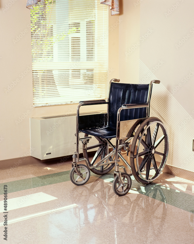 Wheel chair in corner of institutional room with window