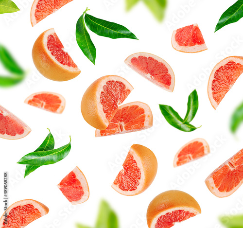 Background of grapefruit pieces and green leaves isolated on white background.