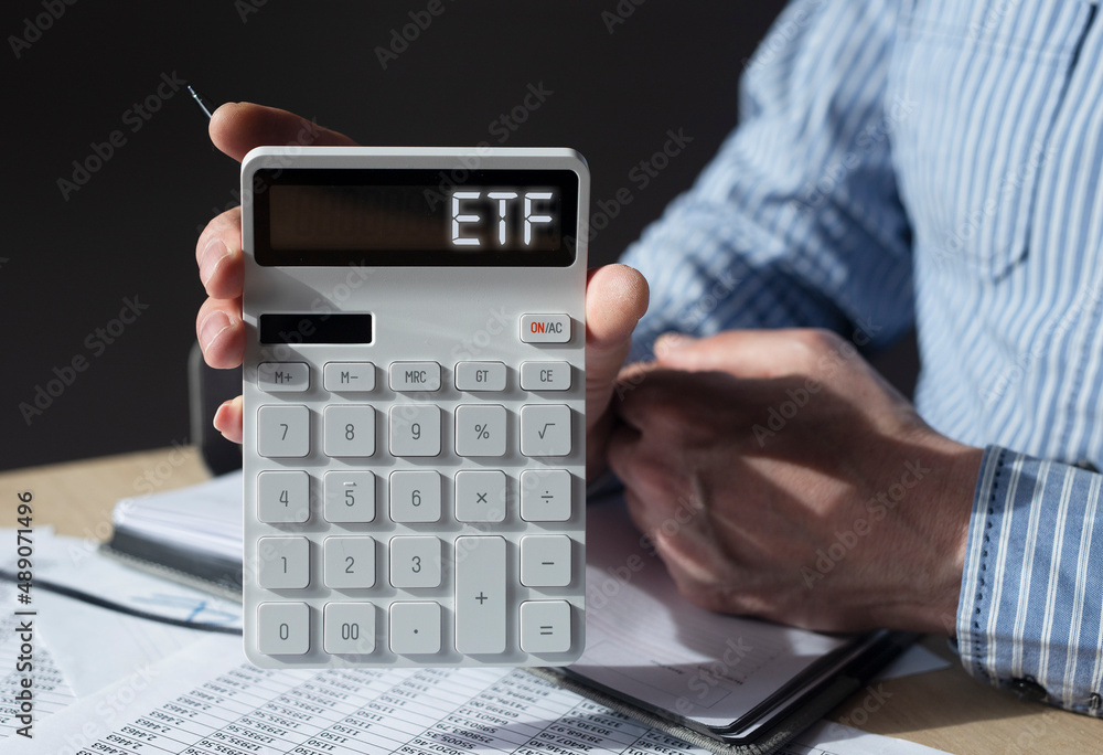 ETF investtments concept. Acronym on calculator in advisors hand. ETF investtments concept. Acronym on calculator in advisors hand.