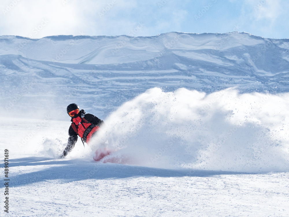 Active man riding snowboard on ski slope with snow splash