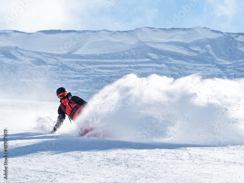 Active man riding snowboard on ski slope with snow splash