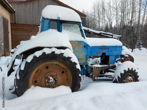 old blue tractor standing covered in snow photo
