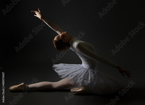 Fototapeta Naklejka Na Ścianę i Meble -  elegant ballerina made a deflection. photo shoots in the studio on a dark background