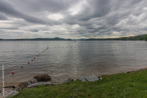 swimming area in lake with mountains and gray sky photo