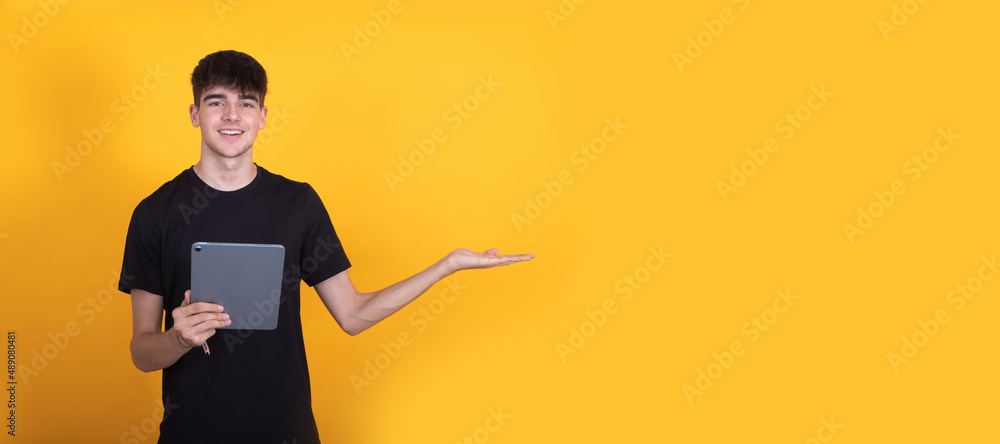 Fototapeta premium teenage student with tablet isolated on background pointing with copy-space