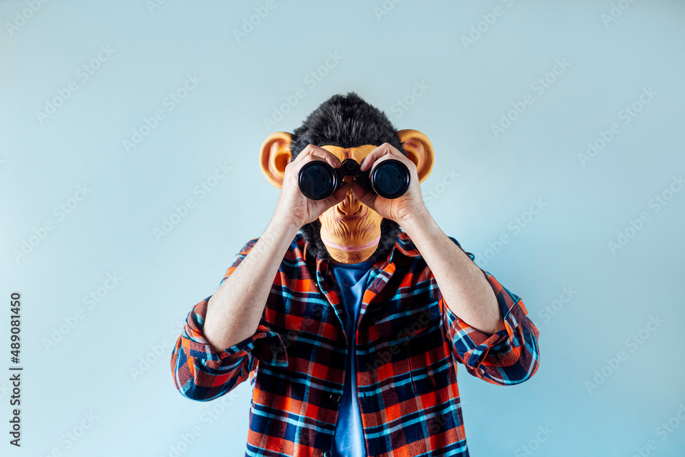 Man with monkey mask using binoculars. Man with monkey mask using binoculars.