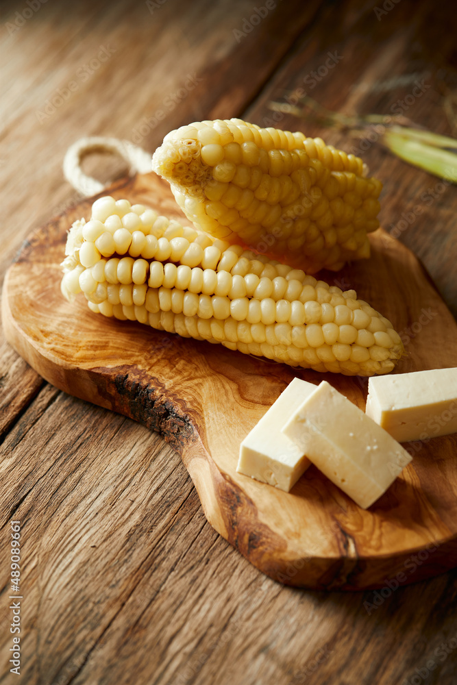 Choclo con queso a typical ecuadorian appetizer that consists of corncob  accompanied by fresh cheese. It's on a wooden and rustic background. Photos  | Adobe Stock