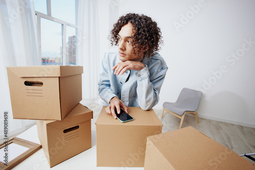 A young man with a phone in hand with boxes moving Lifestyle