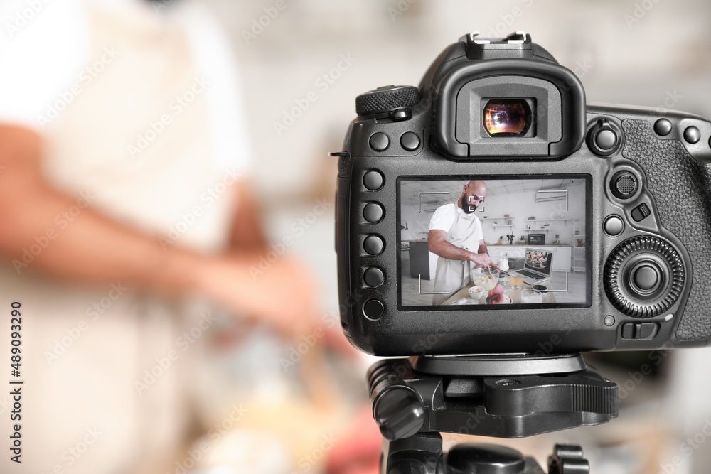 Handsome man making dough on display of photo camera in kitchen, closeup Handsome man making dough on display of photo camera in kitchen, closeup