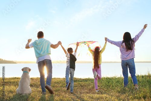 Happy family with kite and cute dog near river