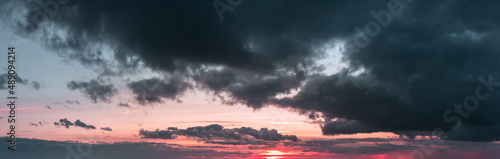 Sunset panorama with dark clouds and red sky