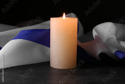 Burning candle and flag of Israel on dark background. Holocaust remembrance day photo