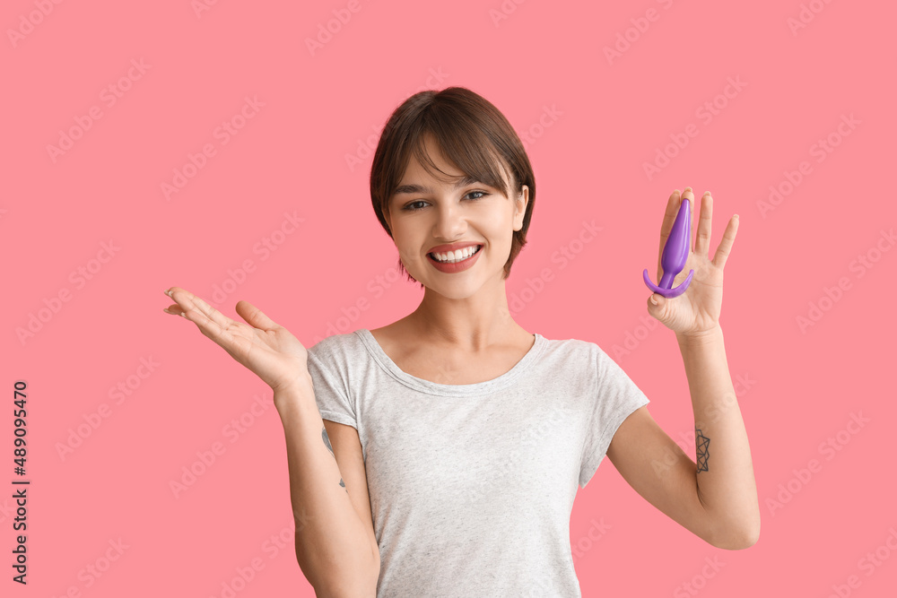 Beautiful young woman with anal plug sex toy on pink background Beautiful young woman with anal plug sex toy on pink background