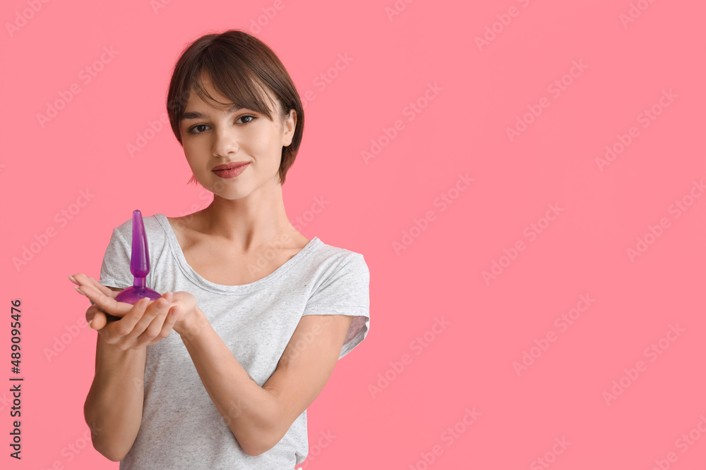 Beautiful young woman with anal plug sex toy on pink background Beautiful young woman with anal plug sex toy on pink background