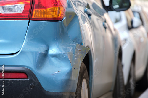 Photography Dented car with damaged fender parked on city street side