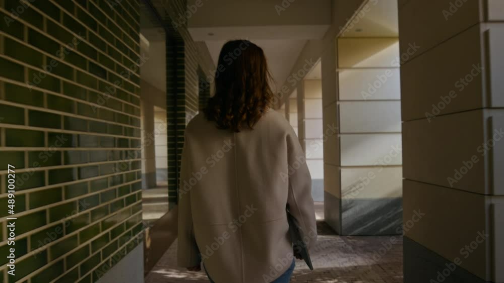 Camera follows young woman, student or manager employee walk through alleyway in university campus or business district, hold laptop in her hand. Concept study abroad or millennial workforce Camera follows young woman, student or manager employee walk through alleyway in university campus or business district, hold laptop in her hand. Concept study abroad or millennial workforce
