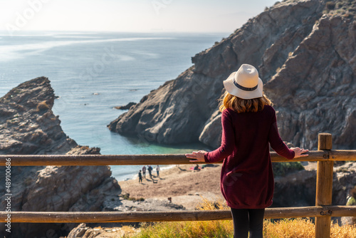 A young tourist girl looking at the beautiful Cala Peñon cut off a virgin and hidden beach in Almería. Mediterranean sea on the coast. Almanzora Caves, Almería