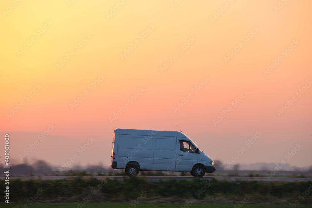 Small cargo van driving on highway hauling goods. Delivery transportation and logistics concept Small cargo van driving on highway hauling goods. Delivery transportation and logistics concept