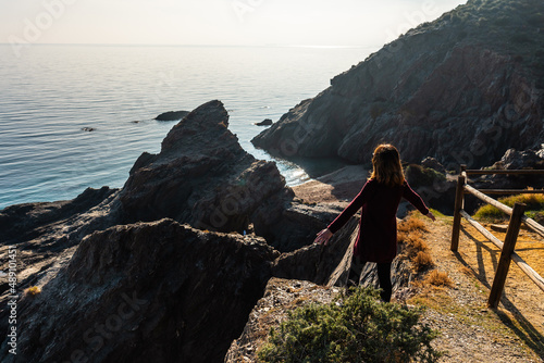 A young tourist looking at the beach in the Almanzora caves from above, Cala Peñon cut a virgin and hidden beach in Almería. Mediterranean sea on the coast, Almería