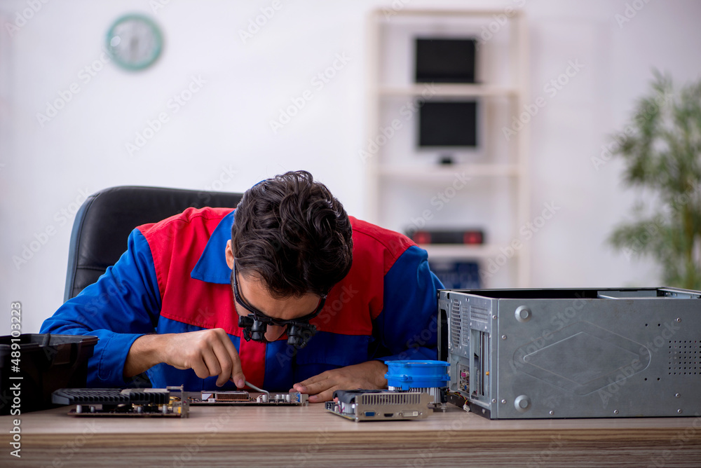 Young male repairman repairing computer Young male repairman repairing computer