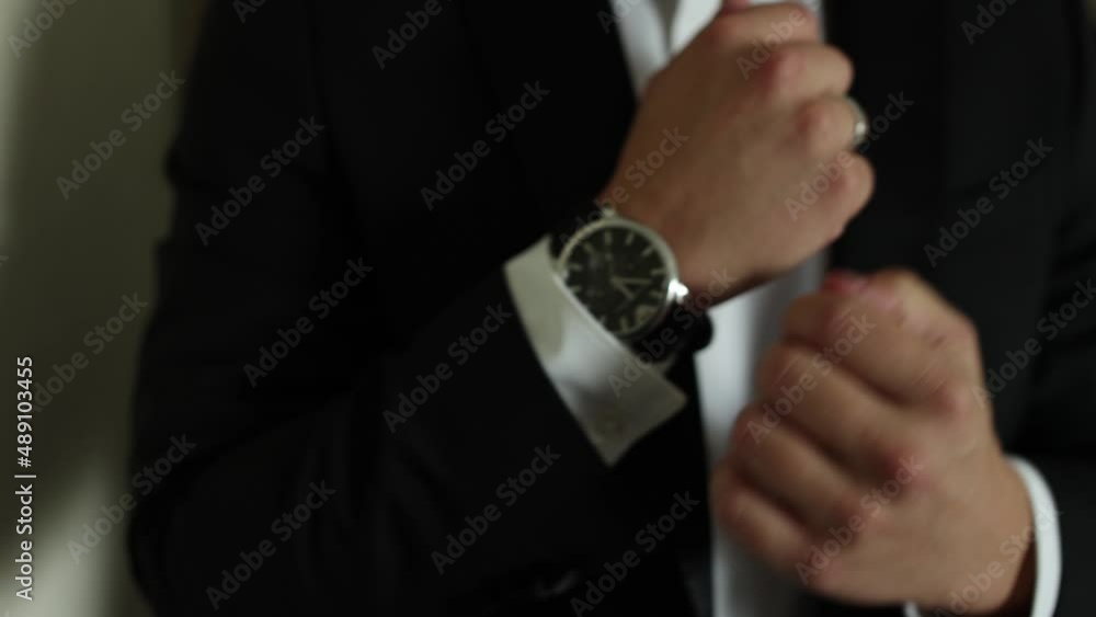 a man in a suit adjusts his watch on his hand a man in a suit adjusts his watch on his hand