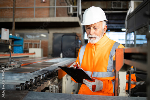 Successful ceramic tile production and factory worker checking quality color and texture.