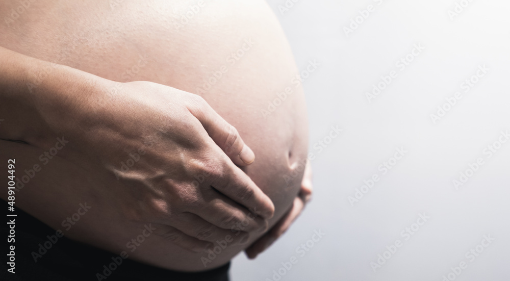 preganant mom are holding hands around her stomach with baby inside. preganant mom are holding hands around her stomach with baby inside.