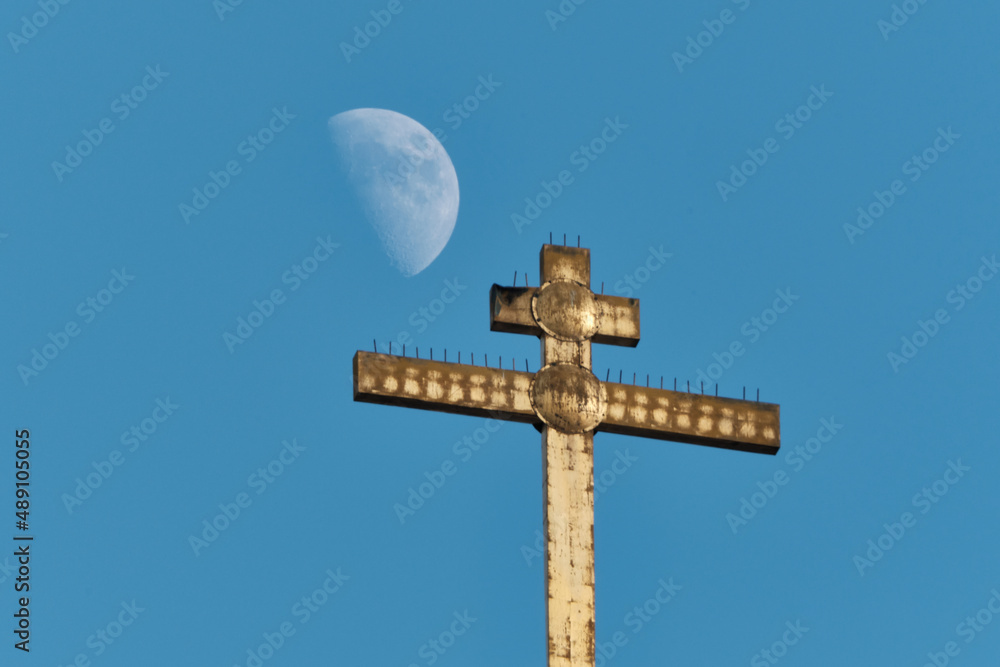 Orthodox cross and waxing gibbous moon in daylight. Russia. Moscow