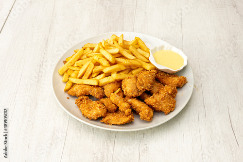 Menu plate with battered chicken strips, French fries and sauce for dipping