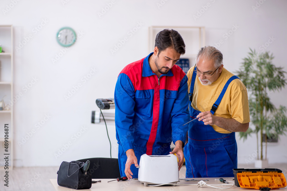 Two male repairmen working at workshop Two male repairmen working at workshop