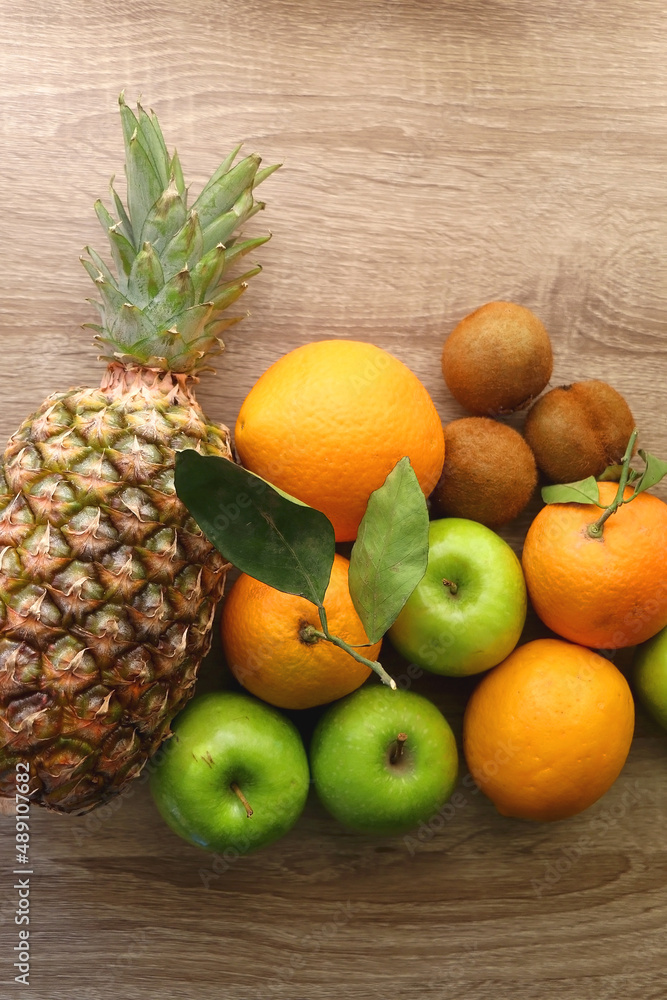 Pineapple, apples, oranges, lemons and kiwis on a wooden table. Top view. Pineapple, apples, oranges, lemons and kiwis on a wooden table. Top view.