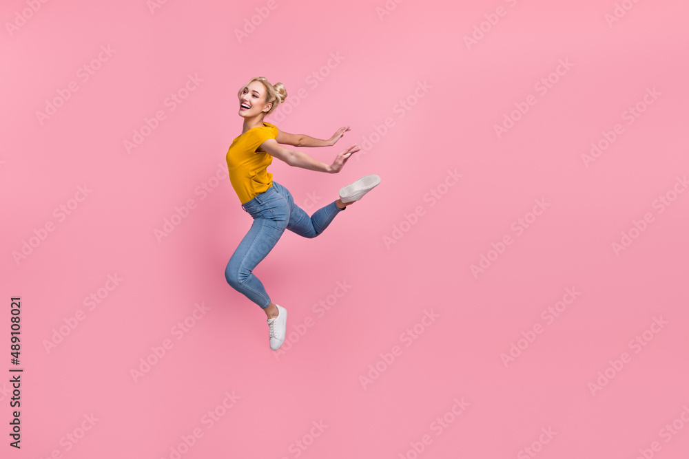 Full size photo of charming cute lady look empty space carefree jumping feel freedom isolated on pink color background