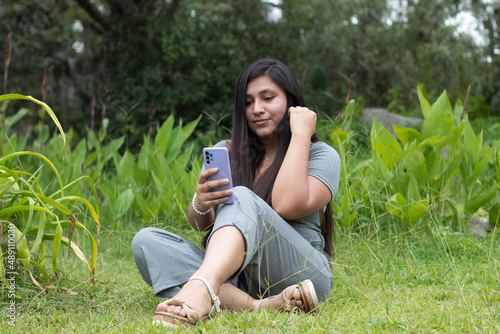 Una mujer  sentada mirando un teléfono inteligente y lee buenas noticias, se siente feliz, se ve encantada, photo
