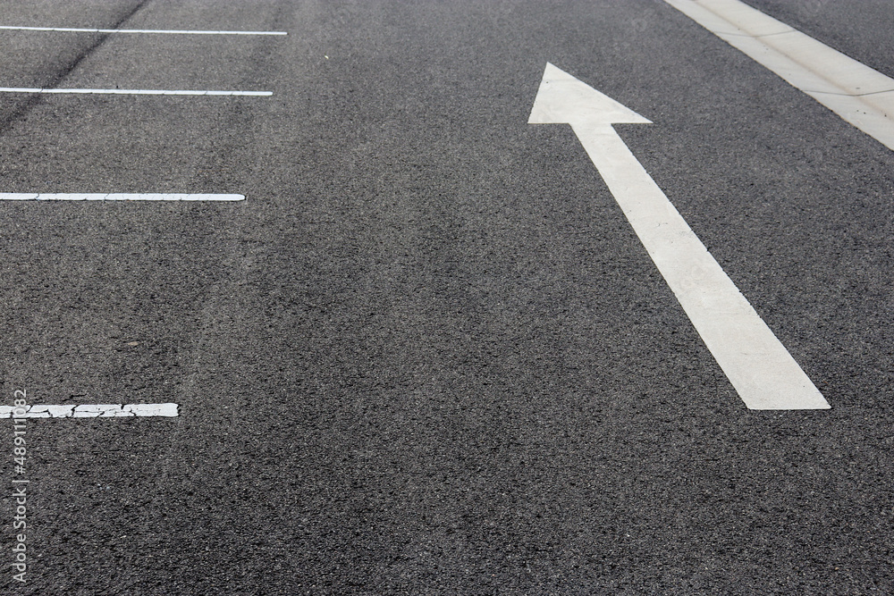 white direction arrow on road in car park