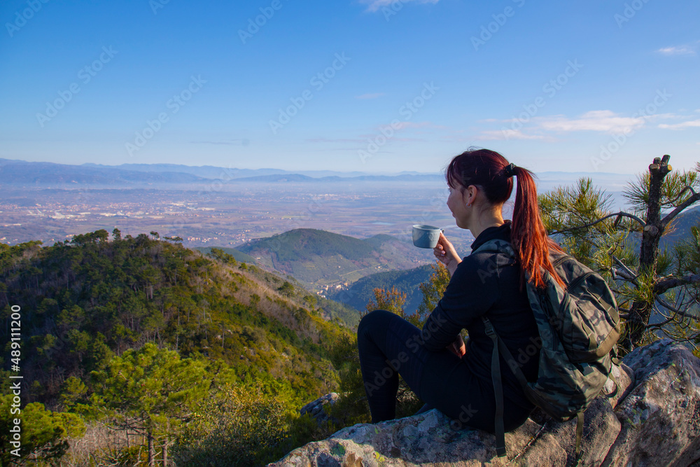 Tracker woman on top of the mountain drinks a hot drink from a thermos Tracker woman on top of the mountain drinks a hot drink from a thermos