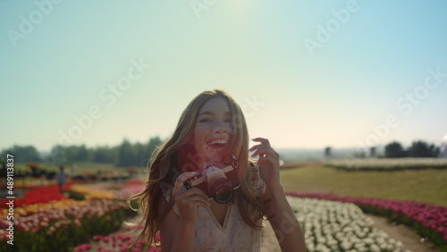 Portrait beautiful lady with camera. Happy woman walking in garden of flowers.
