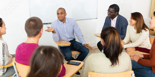 Multi-ethnic group of adult people sitting in circle and sharing ideas during class in ..college