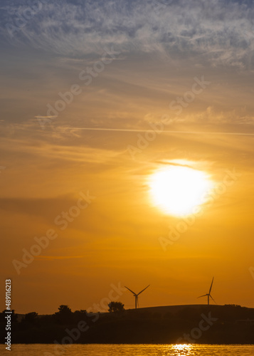 Sunsets on the river with wind turbine on hillside