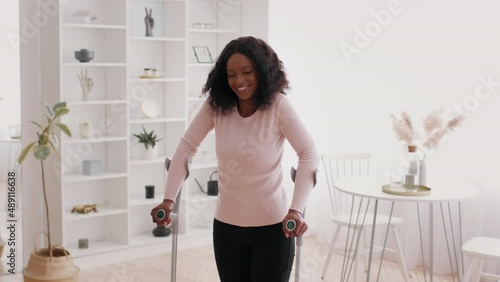 Cheerful Black Woman Standing With Crutches Posing At Home