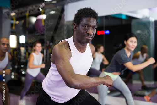 Portrait of sporty man doing cardio exercises training with step platform at fitness center © JackF