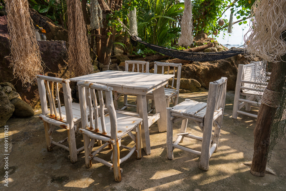 White wooden table and chairs in empty cafe next to sea in tropical beach , Thailand White wooden table and chairs in empty cafe next to sea in tropical beach , Thailand