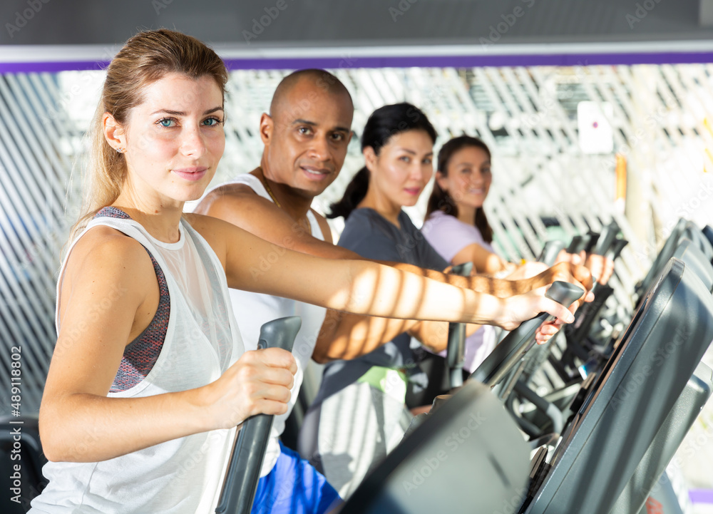 Athletic people running on elliptical trainer in a fitness club