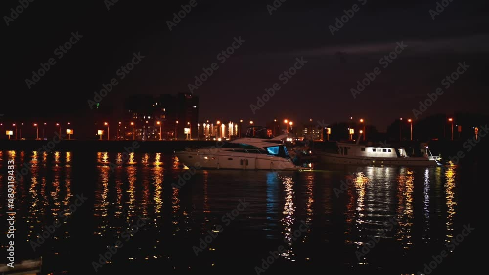 Luxurious modern private yacht and boat at the pier at night. Ship crossing skyline in the harbor in summer awesome nightly. Colorful lights of city glow shine reflected in water wave at nighttime. Luxurious modern private yacht and boat at the pier at night. Ship crossing skyline in the harbor in summer awesome nightly. Colorful lights of city glow shine reflected in water wave at nighttime.